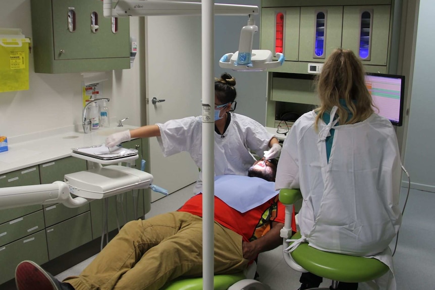 A dentist works on a man in a dental surgery.