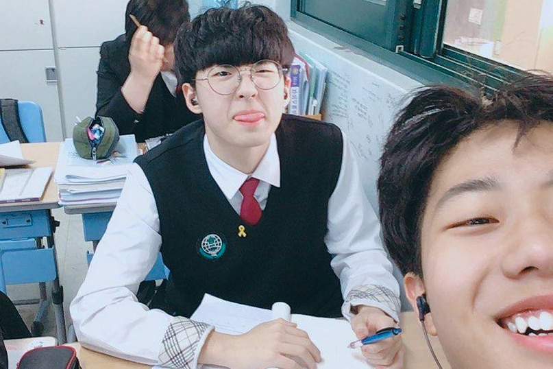 A young male student sticks his tongue out at the camera while his friend takes a selfie