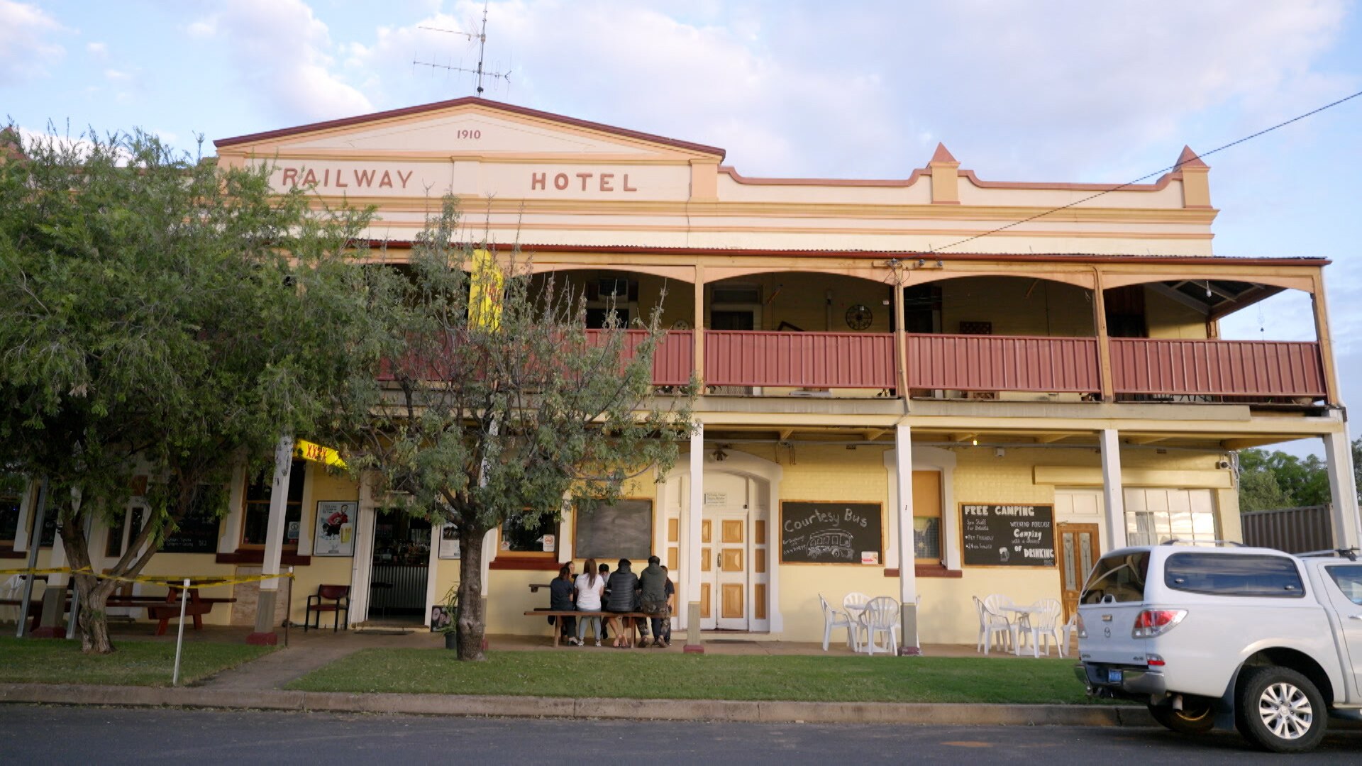 A classic country pub with a group of people sitting on a table outside