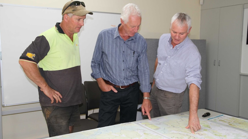 Men look at a map on a table.