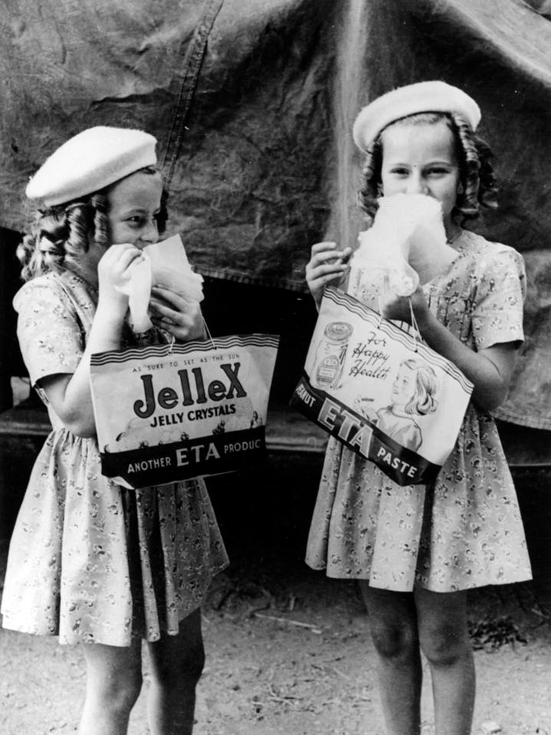 Two young girls in black and white holding Ekka showbags in 1946