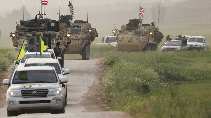 Kurdish fighters from the People's Protection Units (YPG) head a convoy of US military vehicles.
