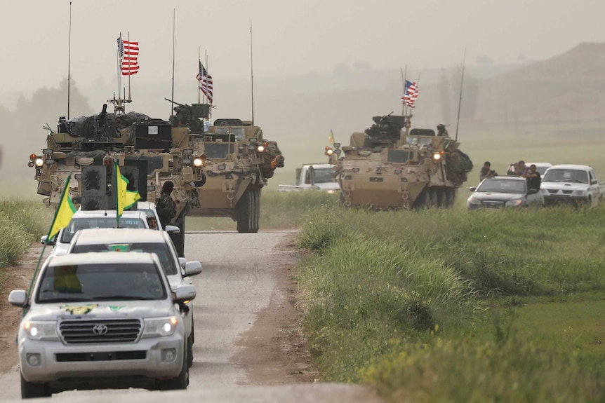 Kurdish fighters from the People's Protection Units (YPG) head a convoy of US military vehicles.