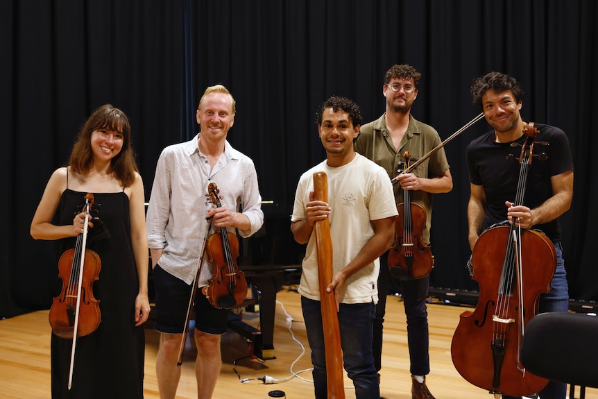 Manduway and members of the Australian String Quartet hold their instruments, smiling at the camera. 