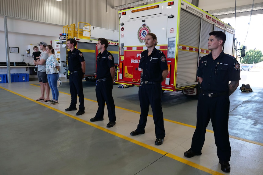 a family stands next to a row of firefighters