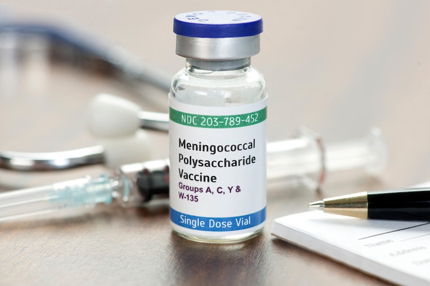 A vial of a meningococcal polysaccharide vaccine on a desk with a stethoscope and a pen. 