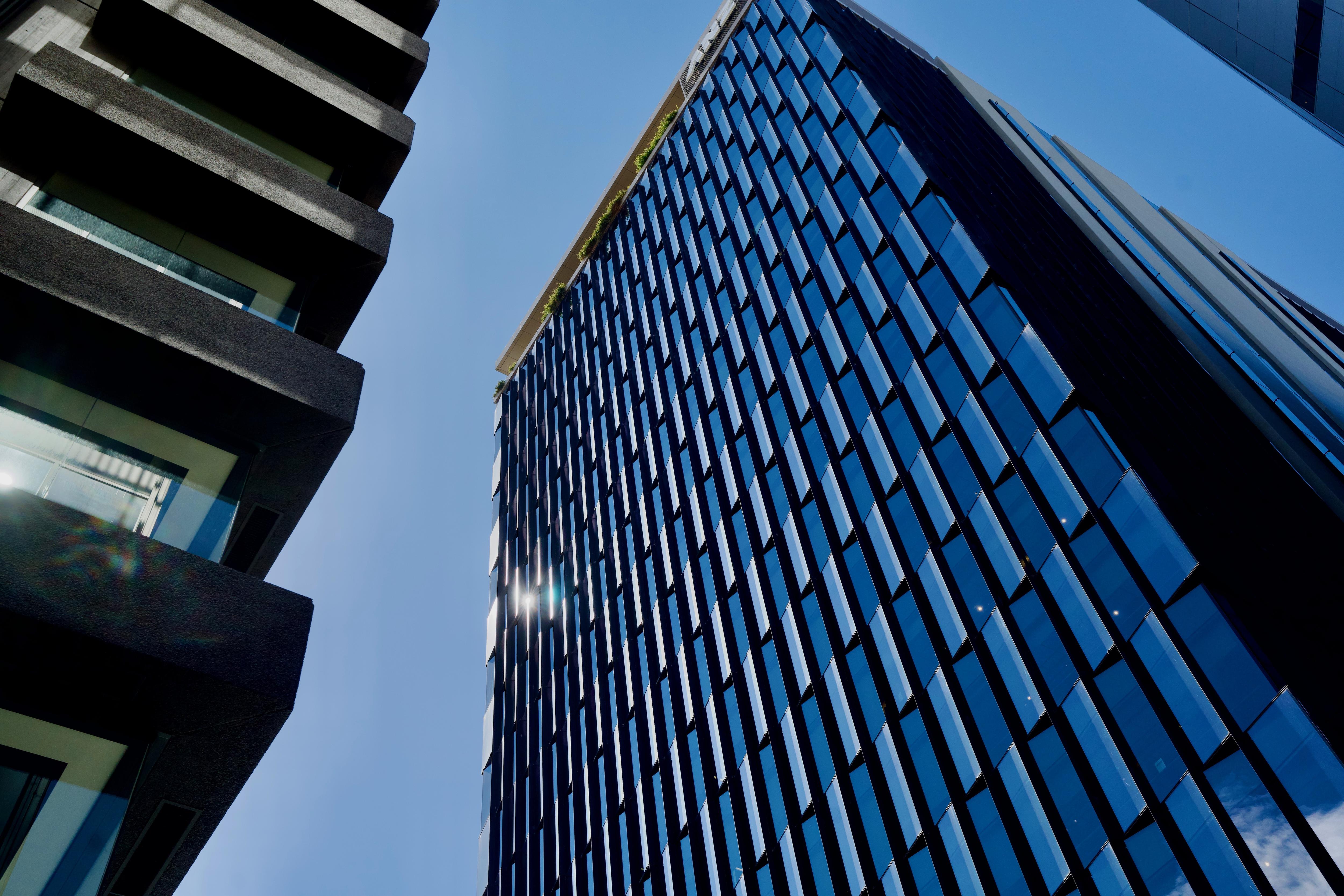 A tall commercial building with large windows next to another tall building