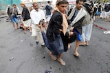 Houthi rebels carry injured man at scene of suicide attack in Sanaa