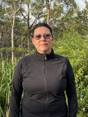 Woman in black activewear standing in a park.