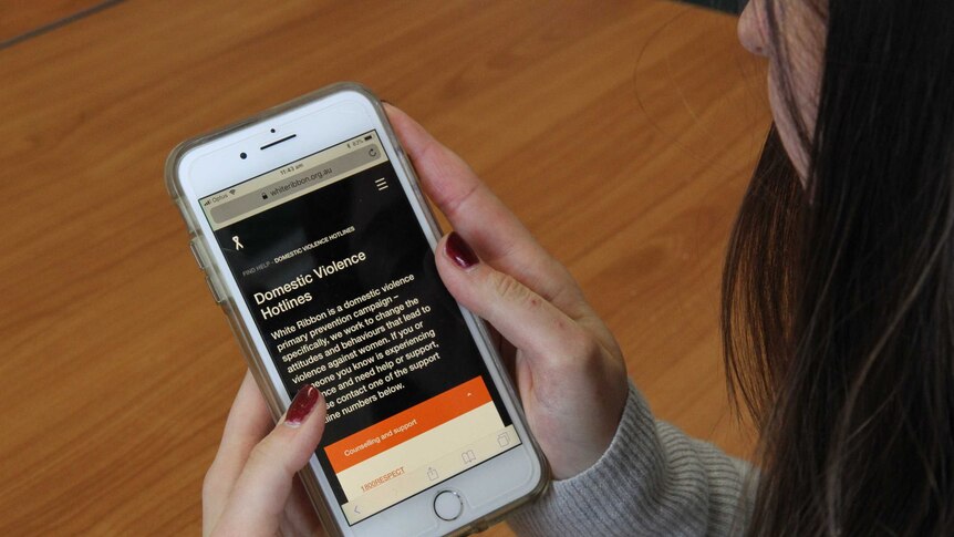 woman looking at her phone with a domestic violence hotline