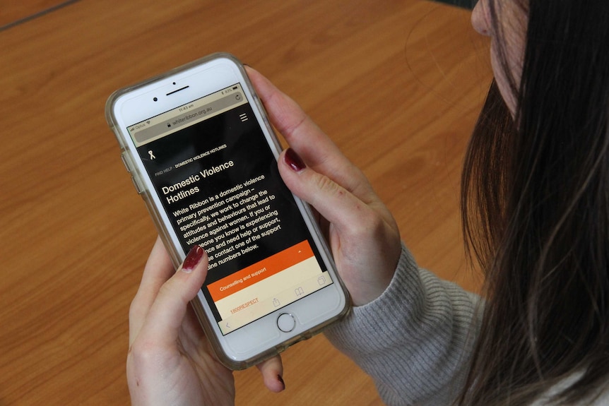 woman looking at her phone with a domestic violence hotline