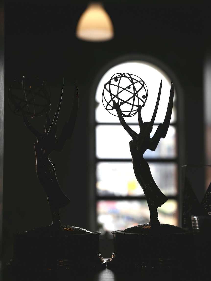 An Emmy statue in front of a window.
