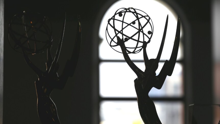 An Emmy statue in front of a window.