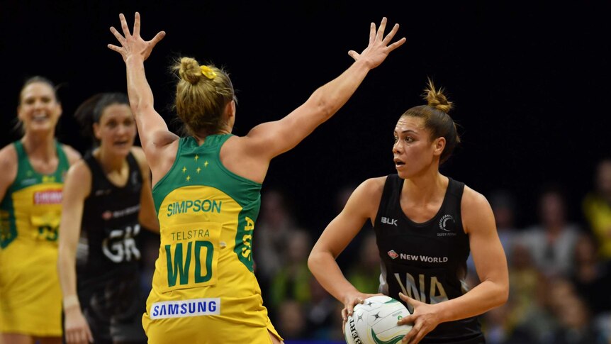 An Australian Diamonds netball player has her arms outstretched in front of a New Zealand player holding a ball.