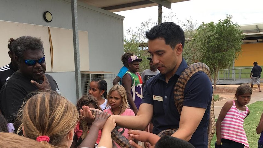 Wiluna Remote Community School Principle Adriano Truscott handles a snake with students.
