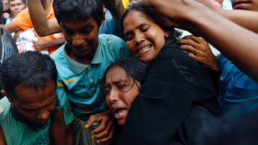 a woman makes an anguished cry as se is jostled in a crowd of people