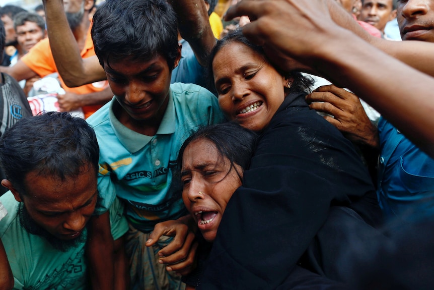 a woman makes an anguished cry as se is jostled in a crowd of people