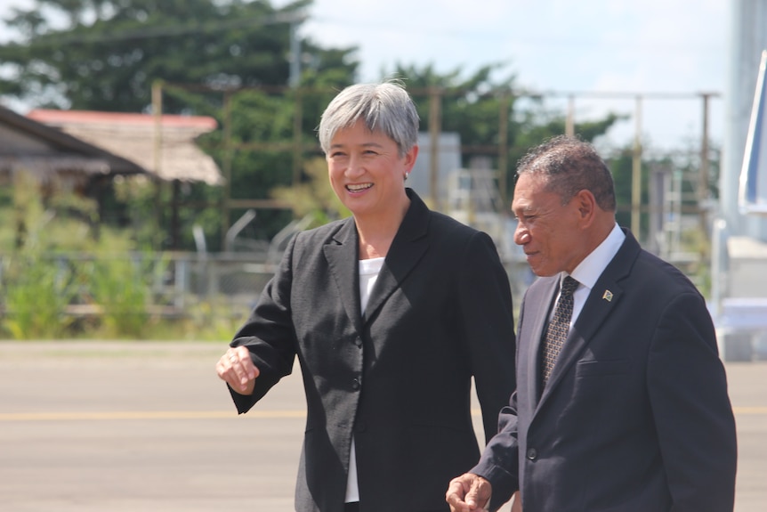 Penny Wong and her Solomon Islands counterpart Peter Shannel Agovaka walk together on tarmac.