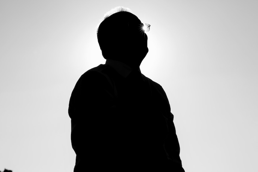 A profile picture of scott morrison in silhouette with a light shining through his glasses