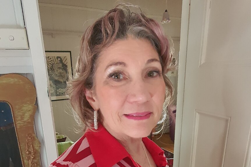 A woman in her 60s in a red striped shirt looking at the camera. 