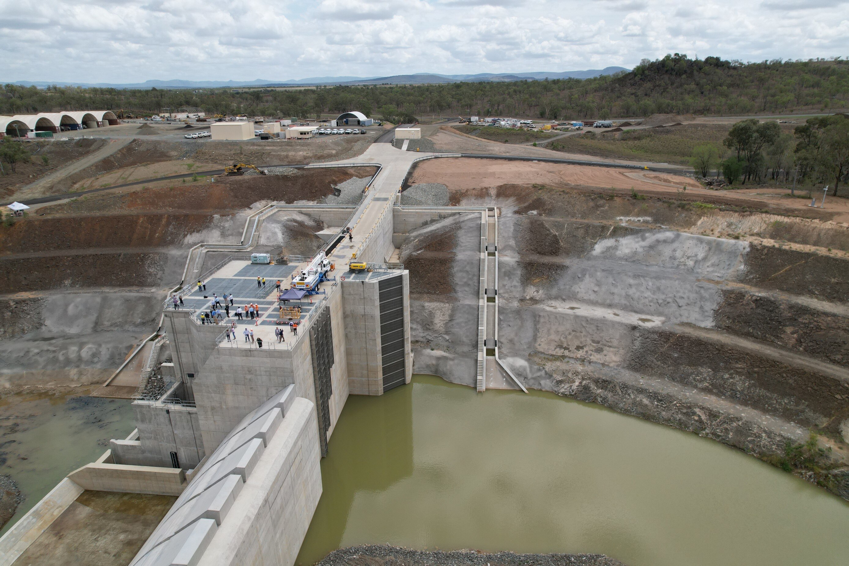 A concrete structure in the middle of a river with a low amount of water in it