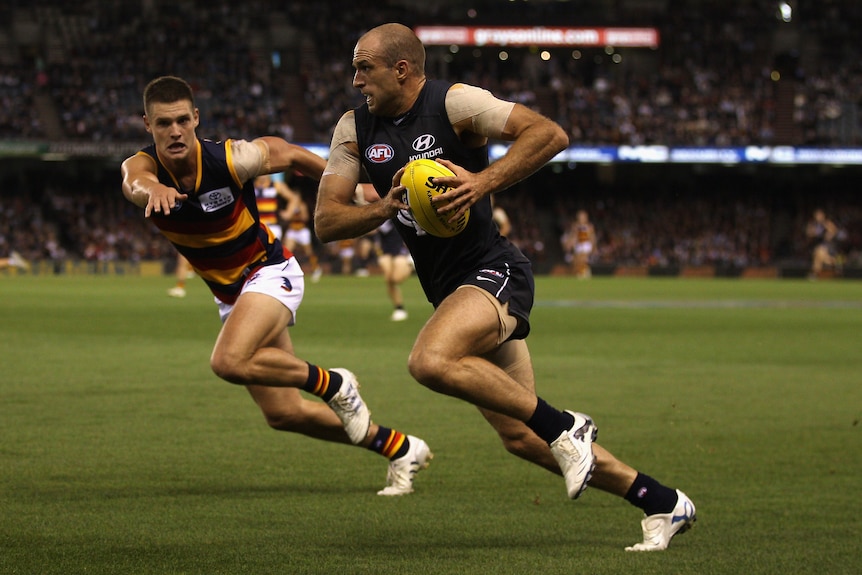Carlton's Chris Judd bursts down the wing carrying the ball, as a defender struggles to follow.