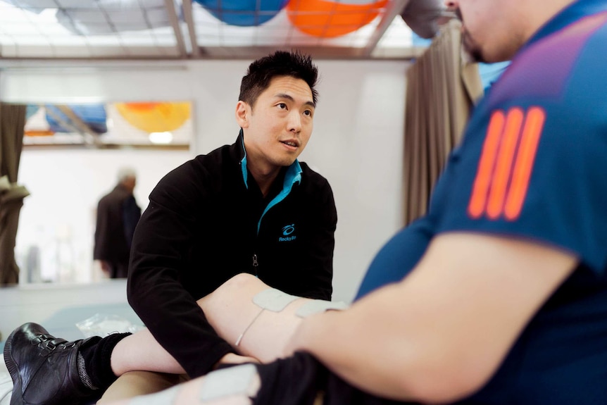 A physiotherapist works on the leg of a patient.