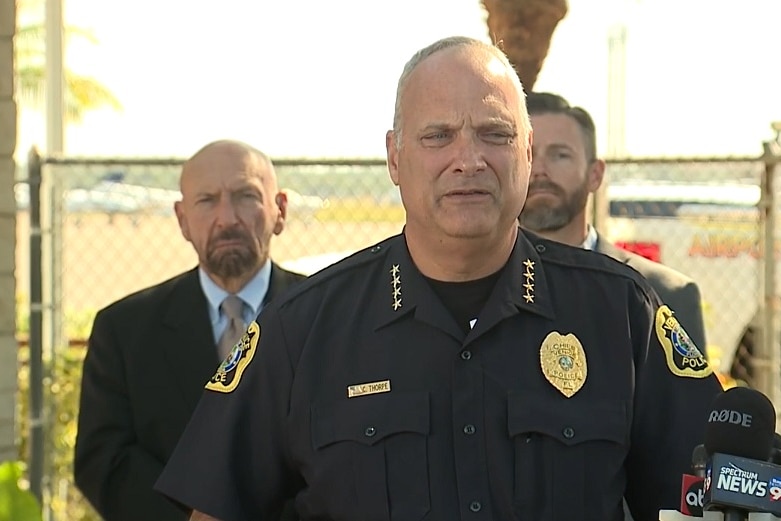 A US police officer, wearing black uniform, stands at a media conference.