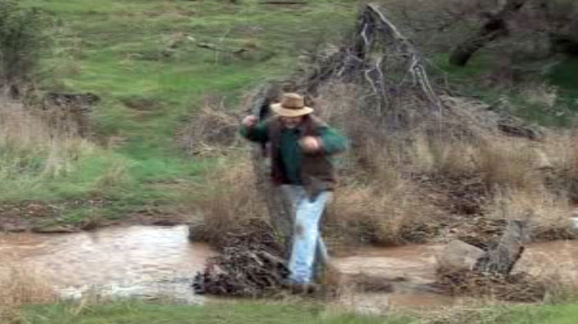 Farmer Paul Camerer jumps over a creek on his property near Geraldton