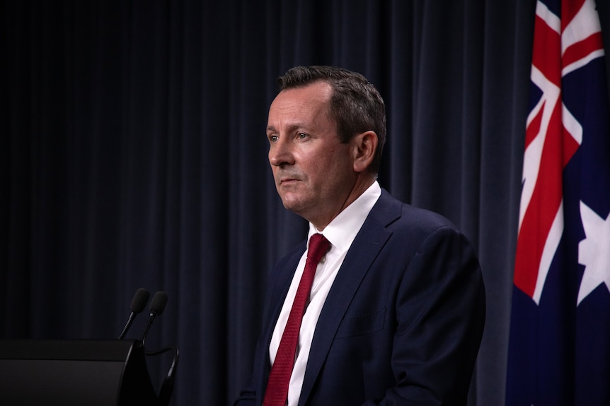A photo of WA Premier Mark McGowan standing in front of an Australian flag.