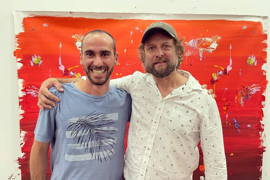 Mr Azimitabar stands next to Ben Quilty smiling in front of a painting.
