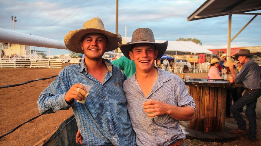 Two boys with drinks in hand, standing on the edge of the arena.