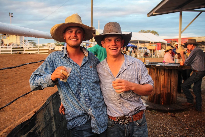 Two boys with drinks in hand, standing on the edge of the arena.