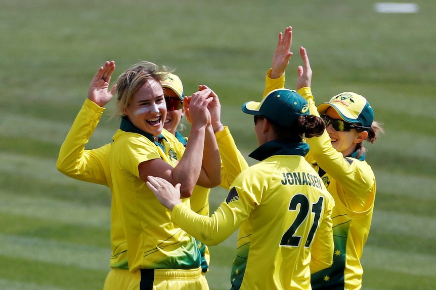 Ellyse Perry smiles and slaps hands with three teammates