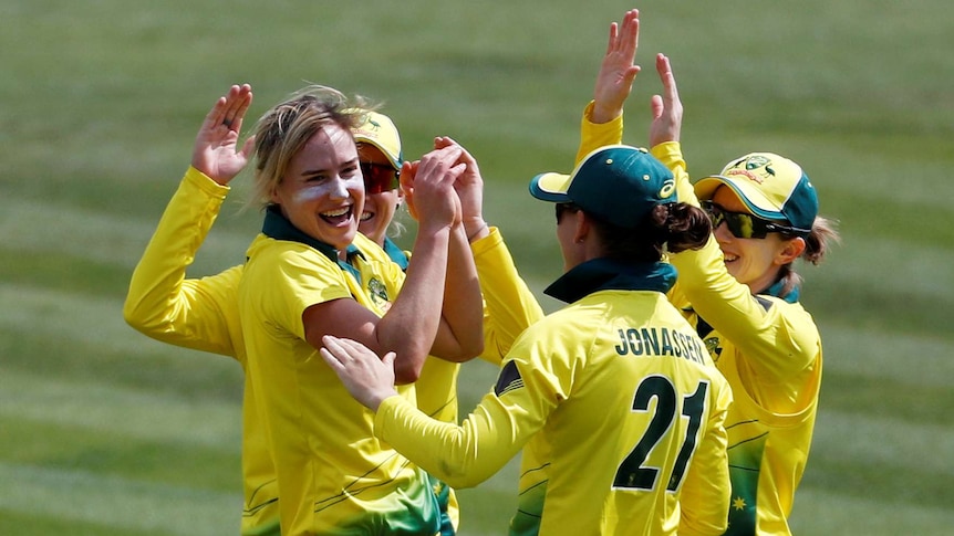 Ellyse Perry smiles and slaps hands with three teammates