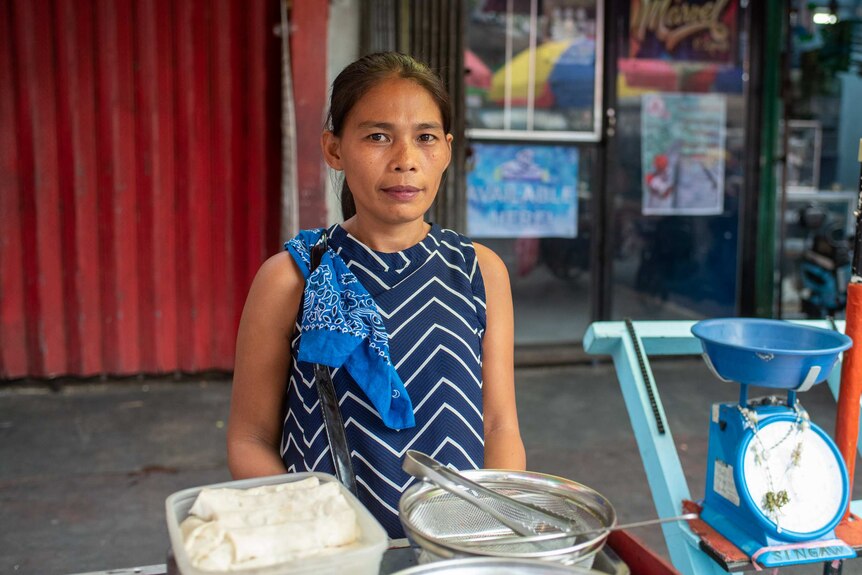 A neat looking woman with a ponytail sells fried food