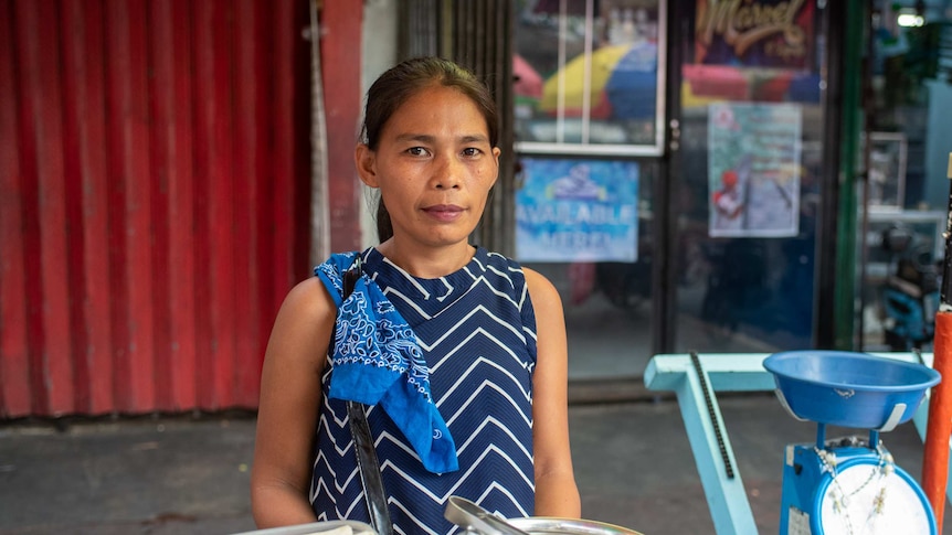 A neat looking woman with a ponytail sells fried food