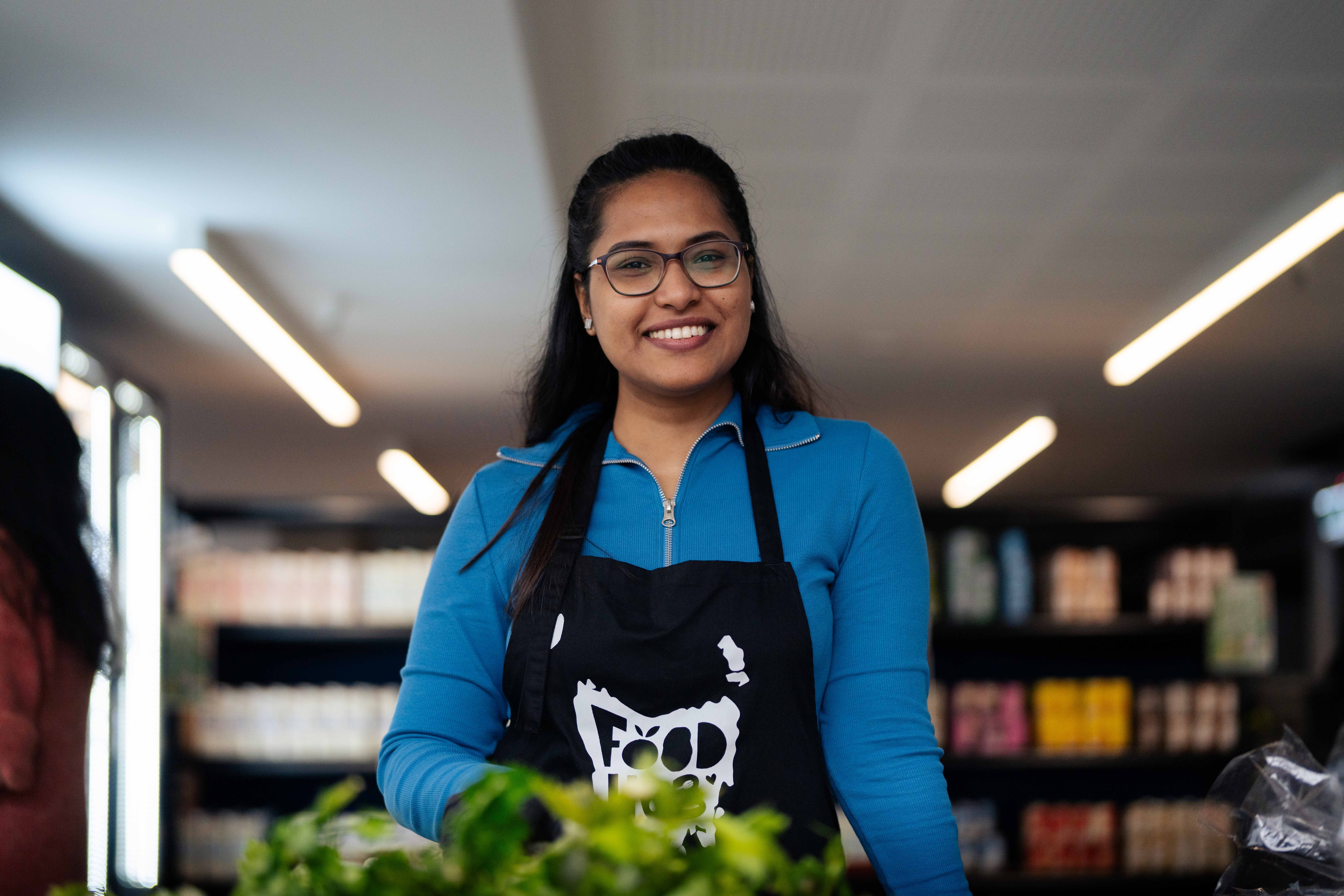 A woman smiles for a photo in a mini grocery store