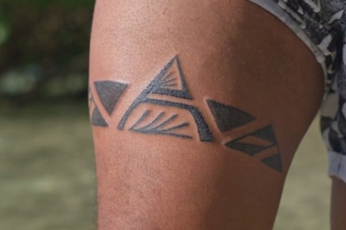 A close up of a man's upper thigh tattooed with geometric style symbols representing mountains and identity