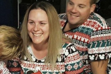 A woman with long blond hair and a colourful top, smiles away from the camera.