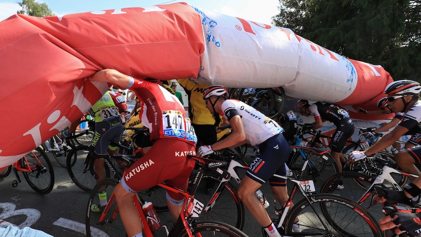 Bikers pass under deflated arch at Tour de France