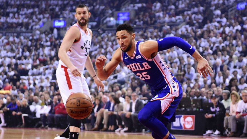 Ben Simmons runs after the ball while wearing a blue singlet as a man in a white singlet looks on