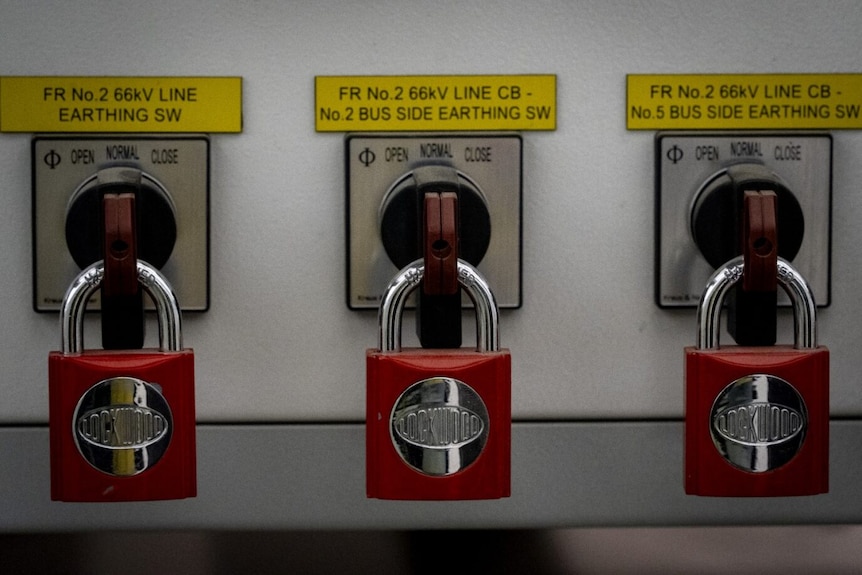 Large red padlocks are shown securing equipment in one of Melbourne's underground tunnels.