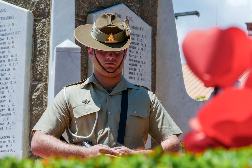 A soldier stands in front of the Townsville memorial on Remembrance Day.
