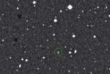 A grainy image of an object in space with a green circle around it