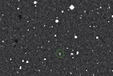 A grainy image of an object in space with a green circle around it