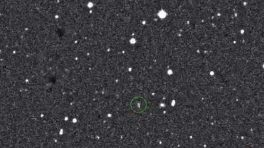 A grainy image of an object in space with a green circle around it