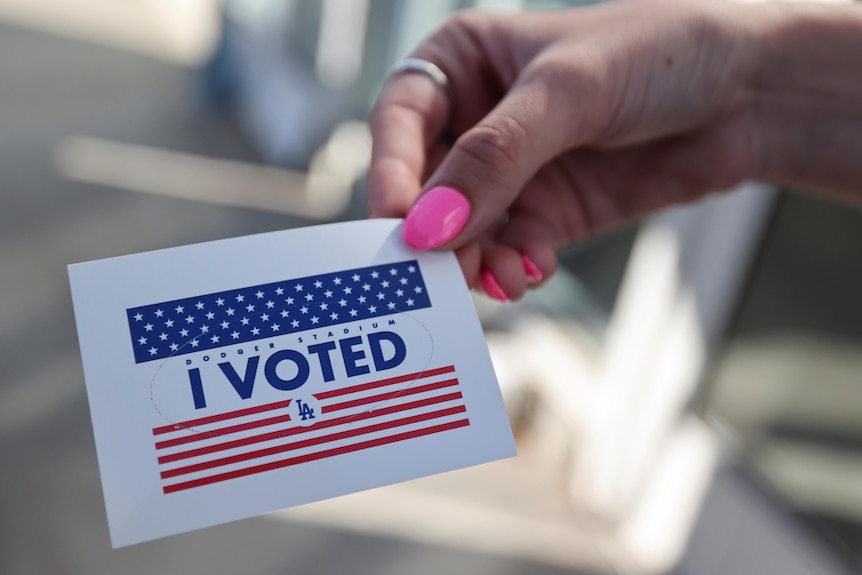 A person holds an "I voted" sticker