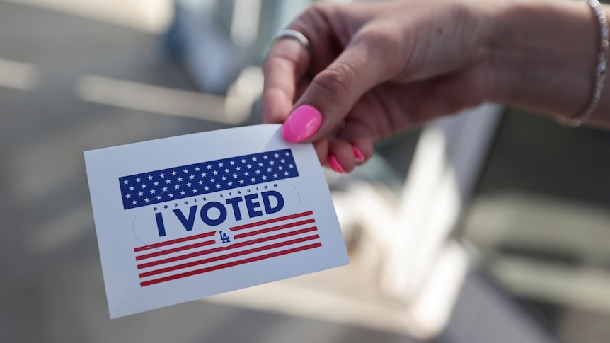 A person holds an "I voted" sticker
