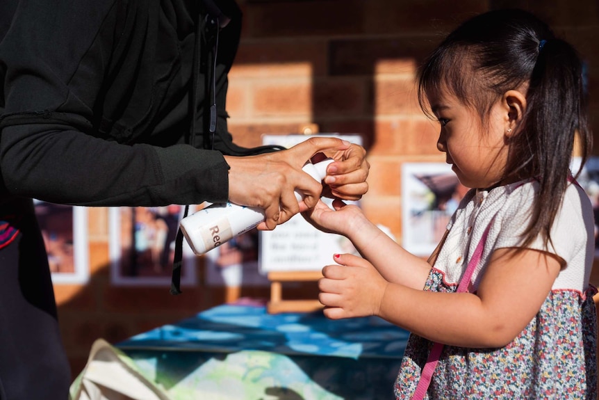 A young girl at a child care centre receives hand sanitiser